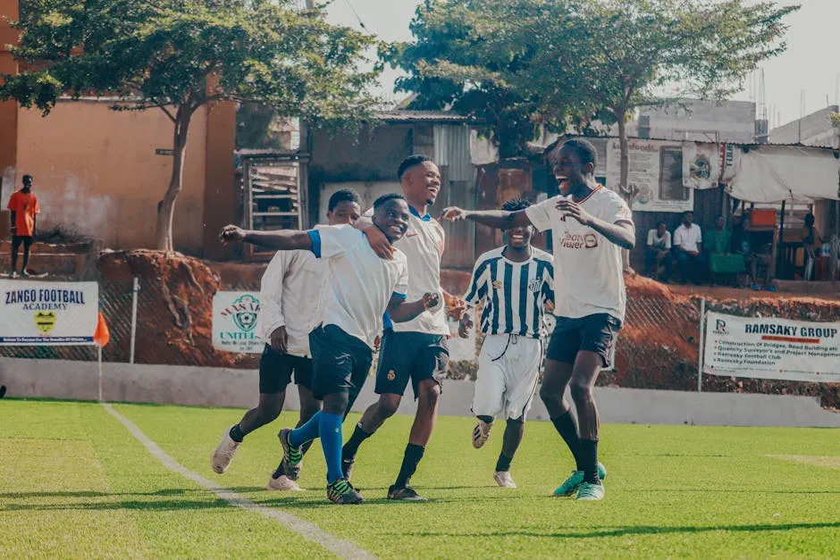 Excited young soccer players celebrating a goal on a sunny day on the football field.