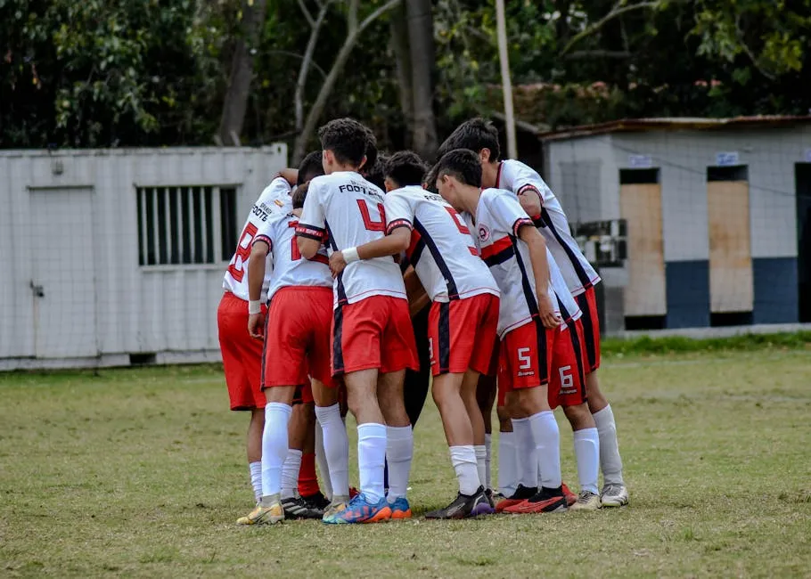 Young soccer players huddle on field in team uniform before game.